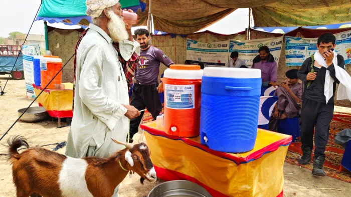 A man drinks water at a heat wave rest stop in Pakistan.