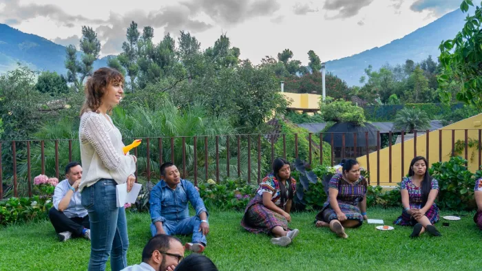 A group of people sit and stand outdoors during a session at a training in Guatemala.