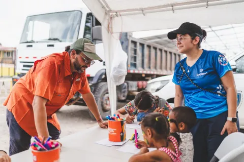 children color on pages as two humanitarian workers look on