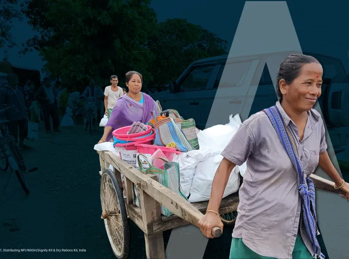 A woman pulls a cart loaded with NFI kits in India.