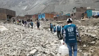 People walk through rubble in the aftermath of landsliding in Peru, to deliver hot meals to affected communities.