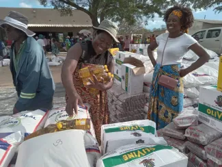 Two women collect food supplies at a distribution in Zimbabwe.