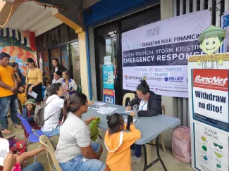 Community members sit at a desk during emergency cash disbursement.