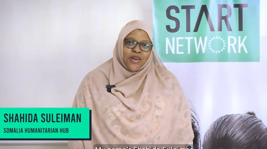 A woman speaks to the camera with Start Network banners in the background.