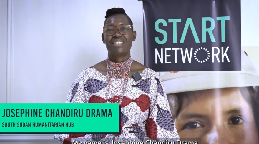 A woman speaks to the camera with Start Network banners in the background.