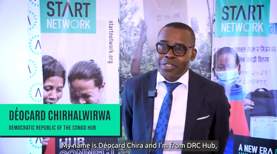 A man is standing in front of banners with Start Network branding, as he gives an interview.