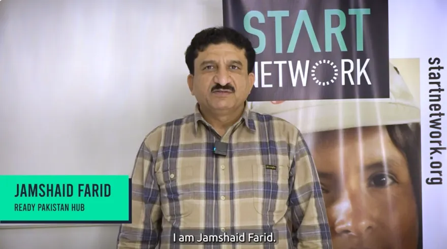 A man is standing in front of banners with Start Network branding, as he gives an interview.