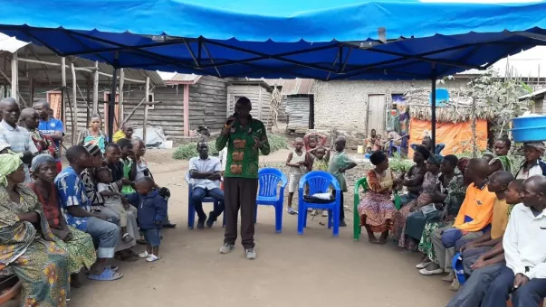 man speaking to people seated around him